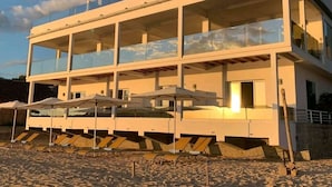 A modern multi-story building with balconies, sun loungers, and a beach setting. - Etoile Blanche (Nosy Be)