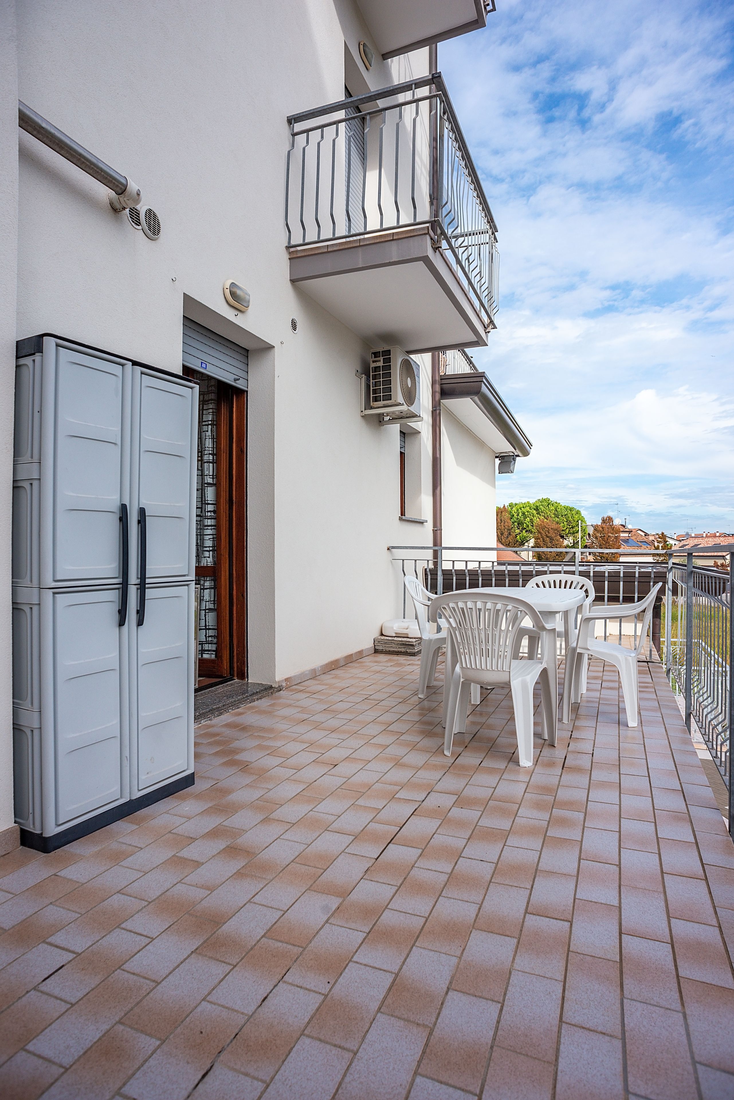 A balcony with a table and chairs, a grey cabinet, and a door with a window.