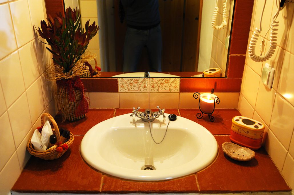 A bathroom with a white sink, a decorative vase, a basket, and a mirror.
