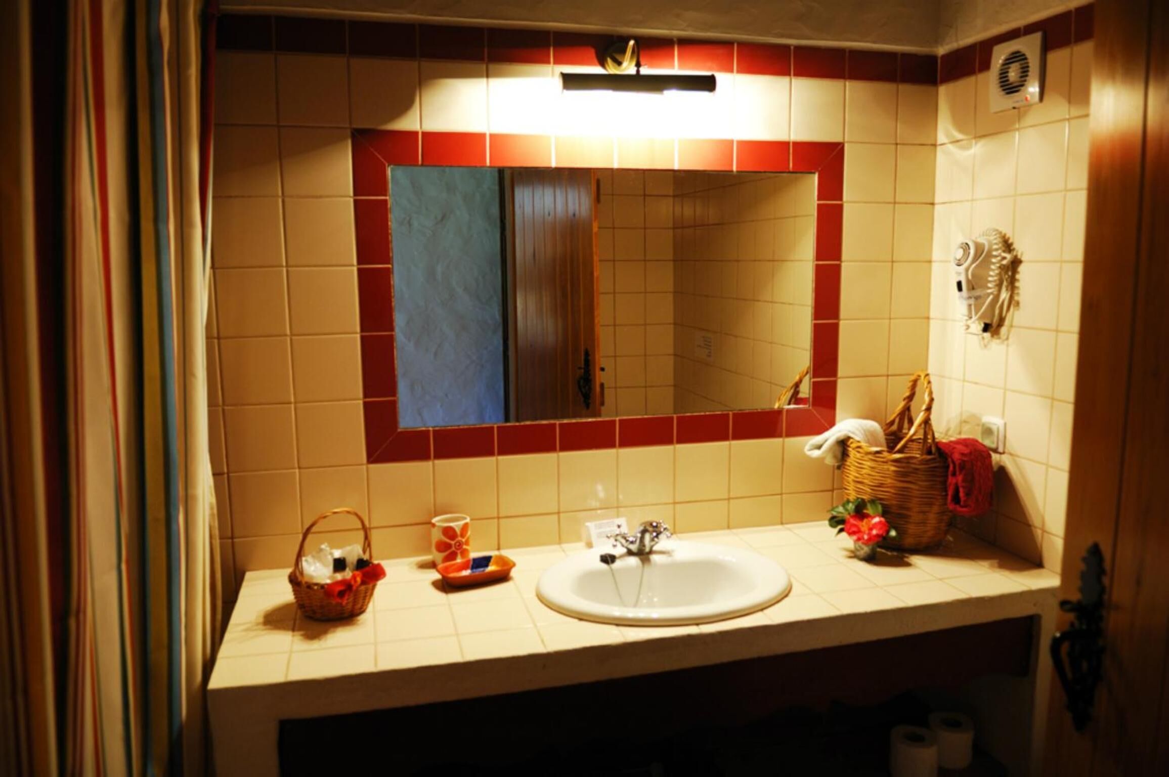 Un baño con lavamanos, espejo y toallero.