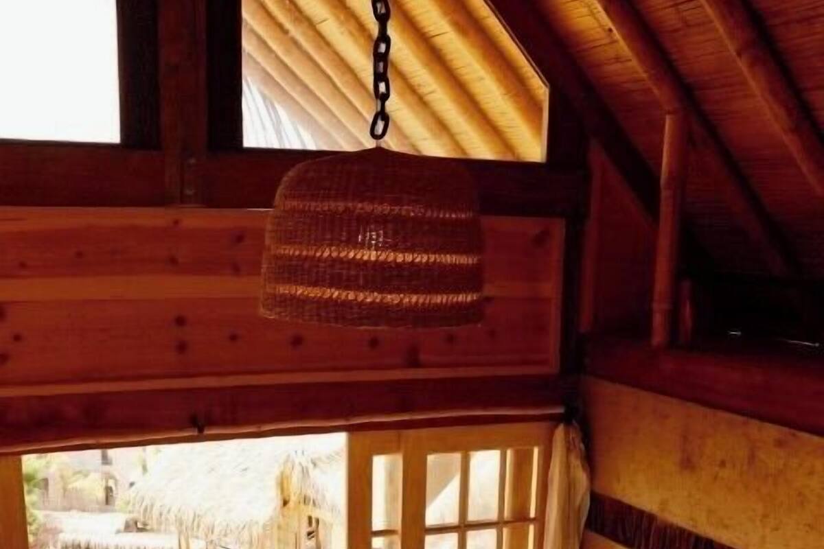 Un dormitorio acogedor con una cama grande, una lámpara colgante y vistas a un espacio exterior con mesa y sillas.