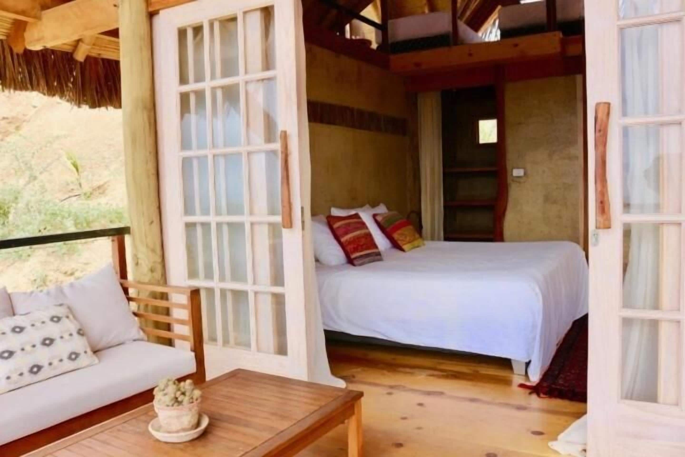 A cozy room with a bed, a sofa, and a small table.