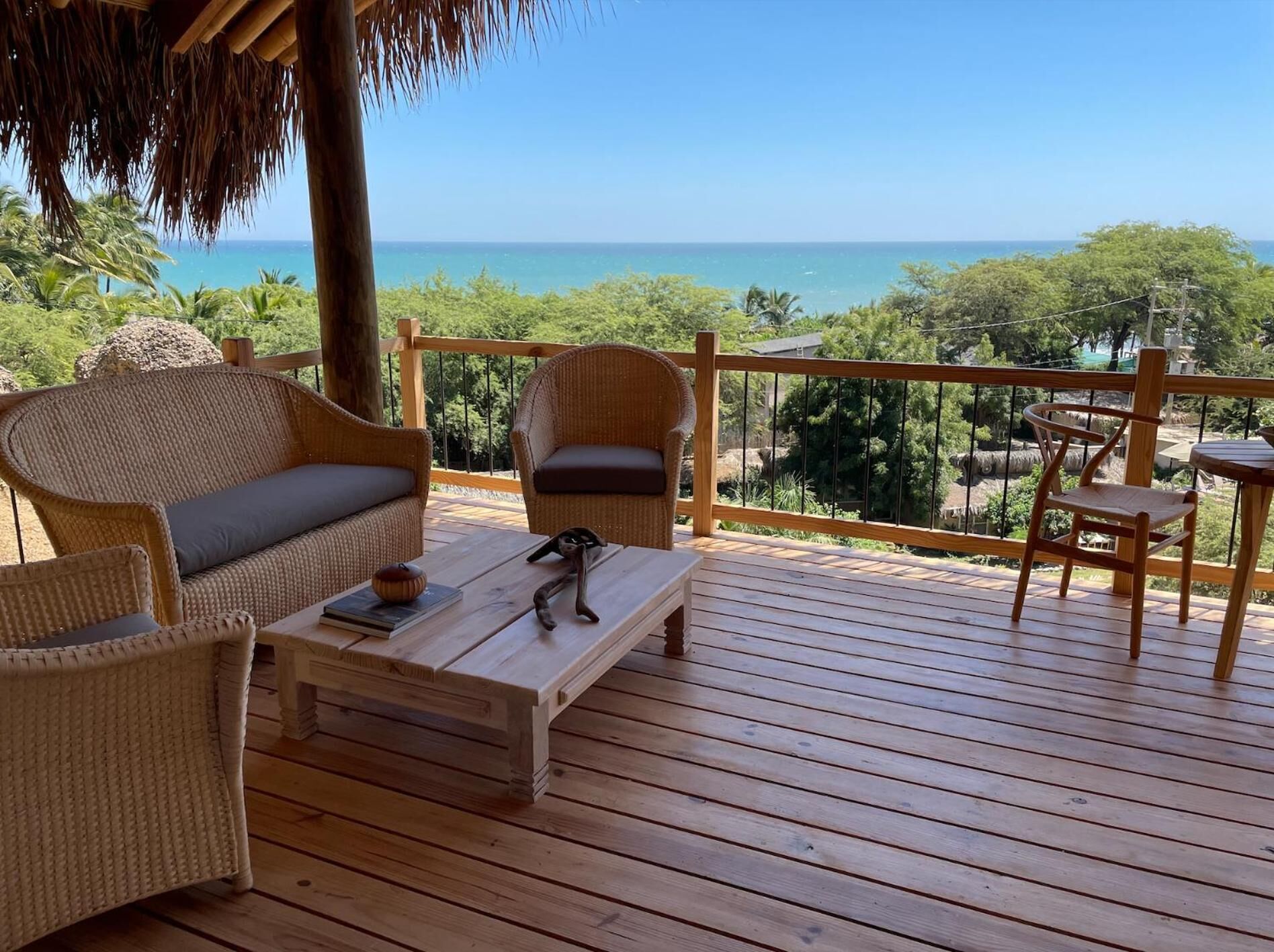 Un pontile di legno con mobili in vimini e vista sull'oceano.