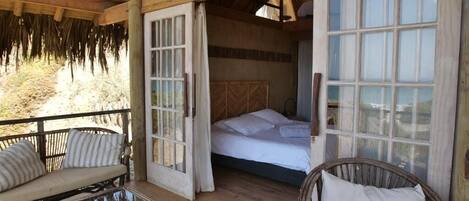 A wooden room with a bed, a sofa, and a glass table.