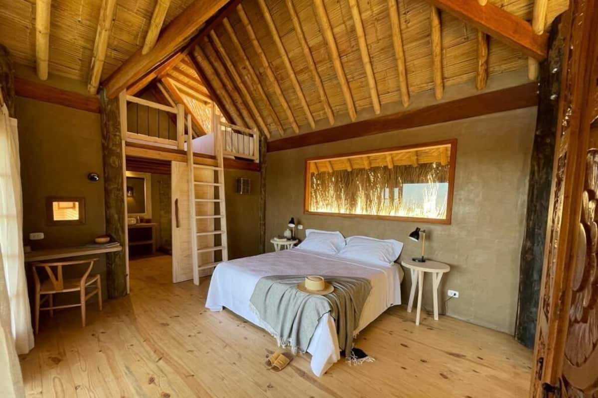 Un dormitorio acogedor con cama tipo litera, pisos de madera, un escritorio y una escalera.