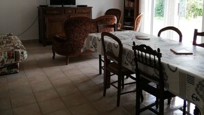 Zona pranzo con tavolo, sedie, televisore e libreria.