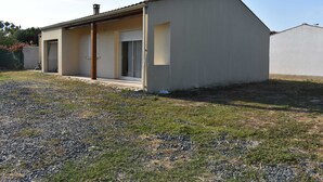 Un edificio a un piano con tetto piatto, un portico coperto e un piccolo giardino con ghiaia ed erba.
