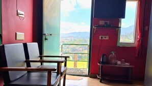 Habitació amb llit, cadira, televisió i finestra que mostra vistes del camp.