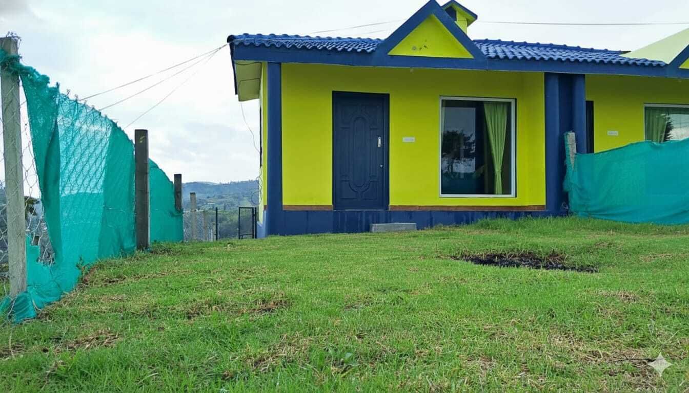 A single-story house with a blue roof and yellow walls, surrounded by a green fence.