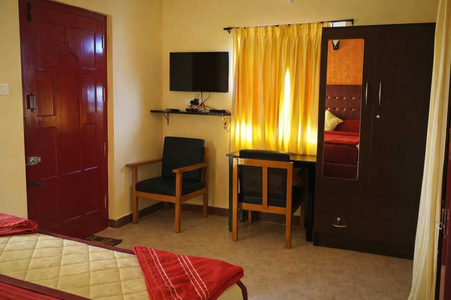 Una habitación de hotel con cama, escritorio, silla, televisor y armario.