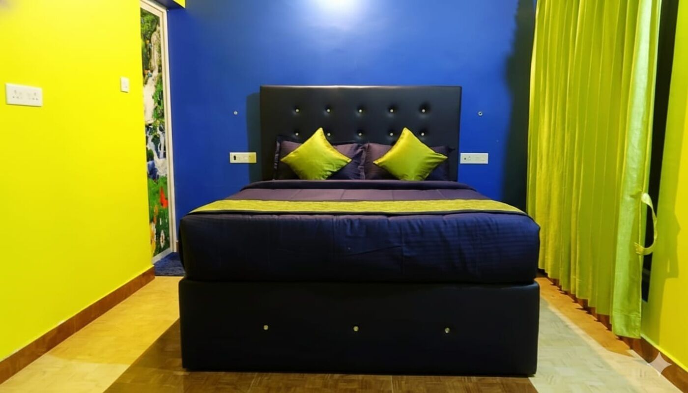 A bedroom with a large bed, bright yellow walls, and a blue headboard.