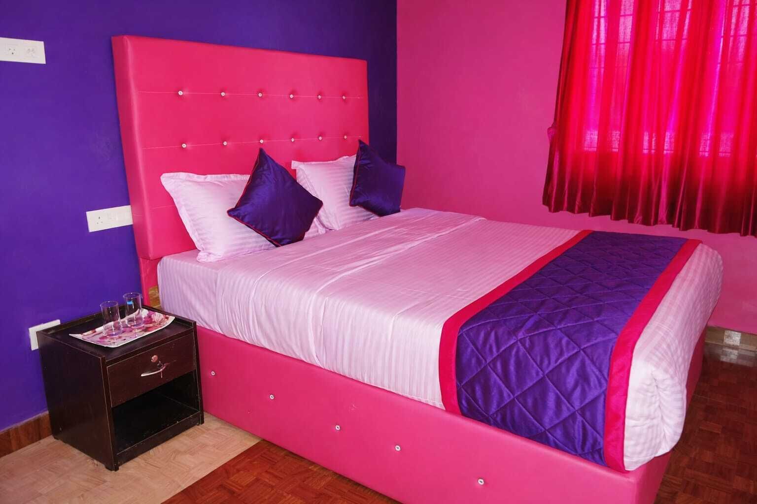 Una cama con cabecera rosa y colcha acolchada morada.
