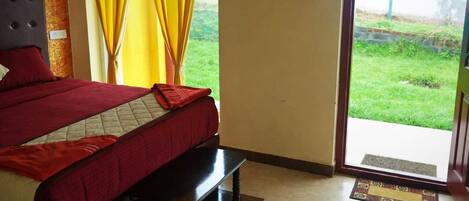 Un dormitorio con cama, mesita de noche, ventana con cortinas amarillas y vista a un paisaje verde.