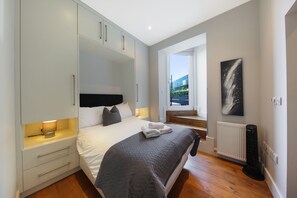 A bedroom with a bed, bedside table, wardrobe, radiator, and a window with a view. -  Executive Apartments in Central London Euston FREE WiFi by City Stay Aparts (London)