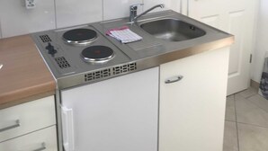 Una cocina compacta con un lavamanos de acero inoxidable, dos hornillas y una pequeña encimera.
