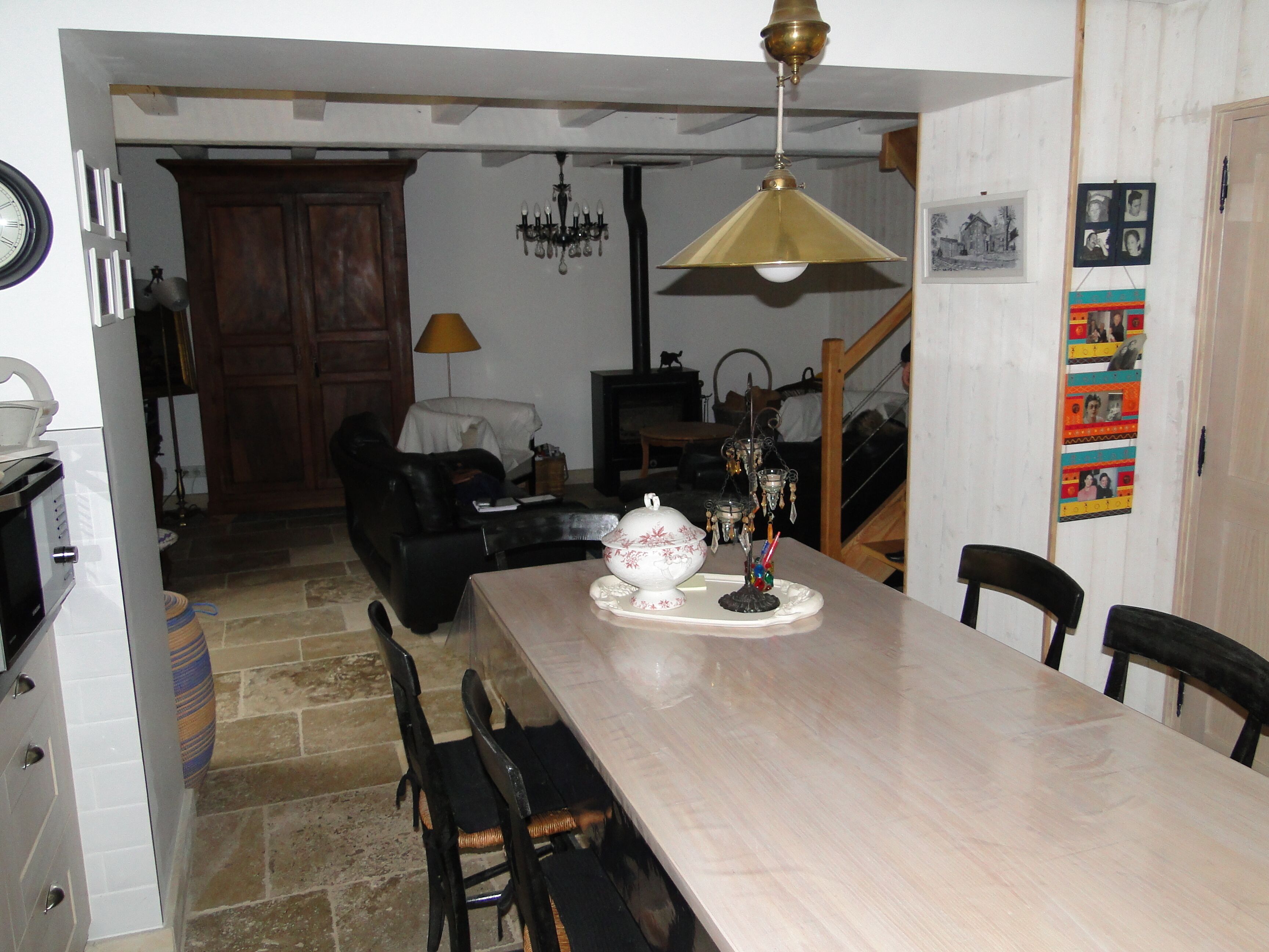 A dining area with a wooden table, chairs, a chandelier, and a decorative centerpiece.