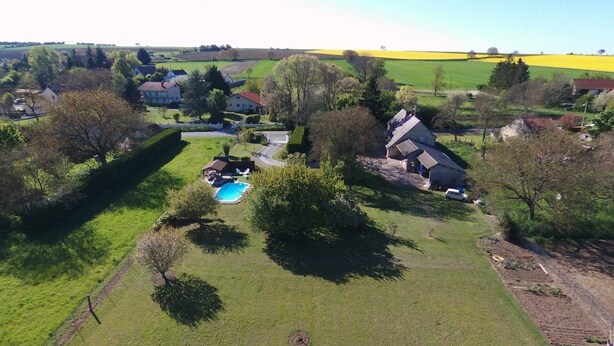 Vista aérea de una propiedad rural con piscina, varias casas y campos aledaños.