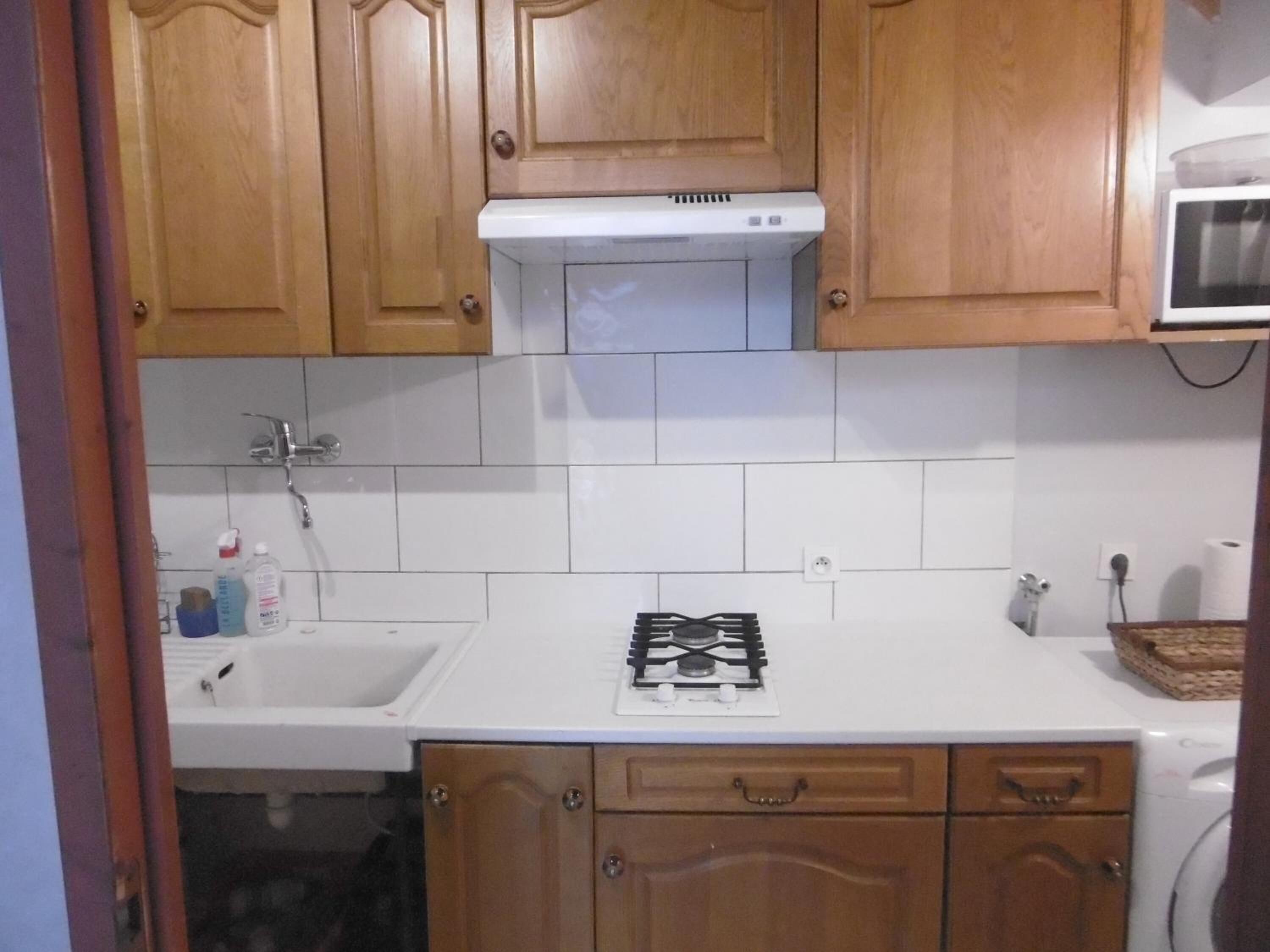 A kitchen with wooden cabinets, a white countertop, a gas stove, a microwave, and a sink.