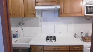 A kitchen with wooden cabinets, a white countertop, a gas stove, a microwave, and a sink.