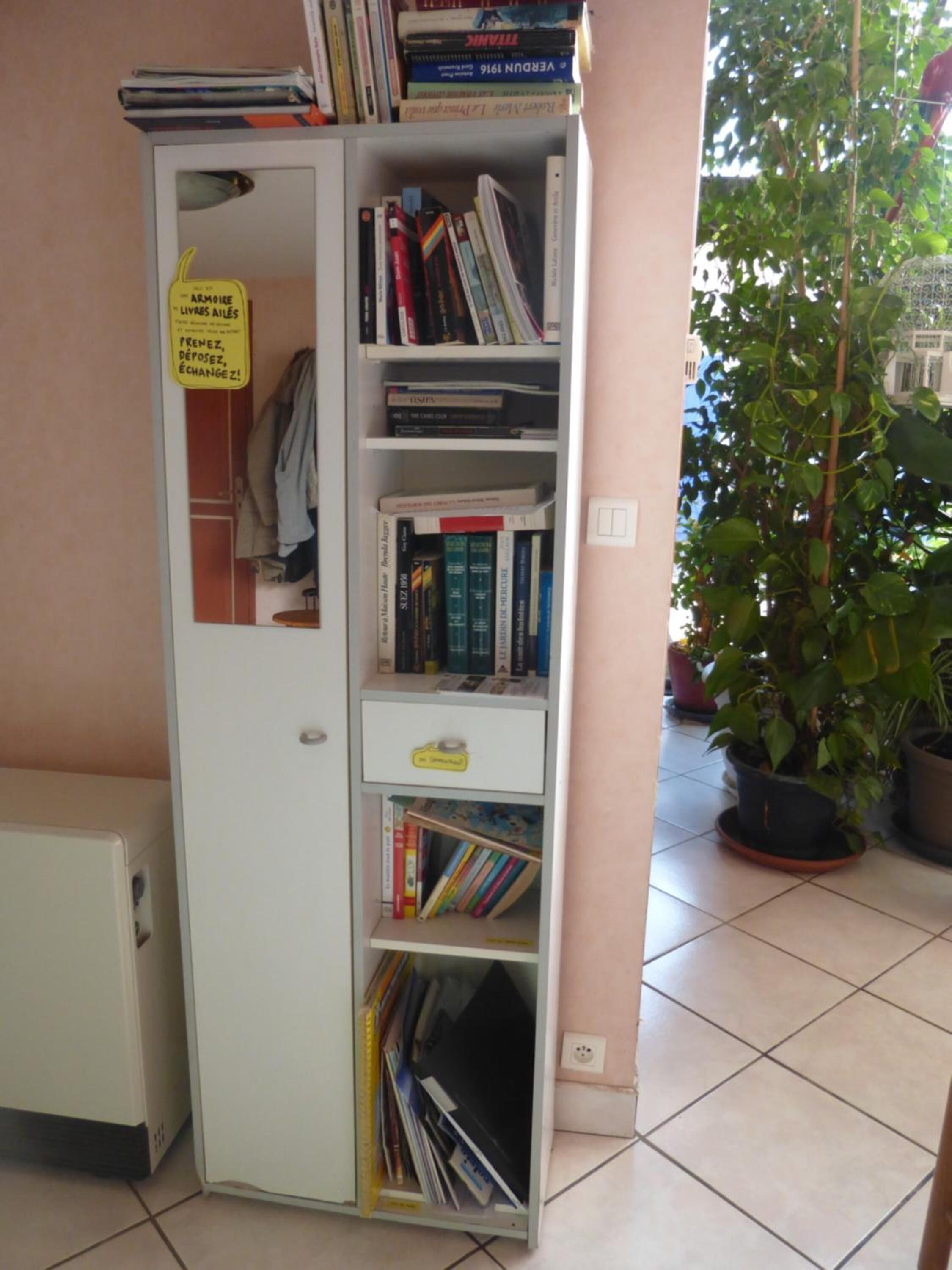 Une bibliothèque compacte dotée de plusieurs étagères, d’une petite porte et d’une inscription en français.