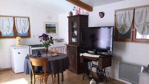 Ein Essbereich mit Tisch, Stühlen, einem Fernseher, einem Schrank und einem kleinen Kühlschrank.