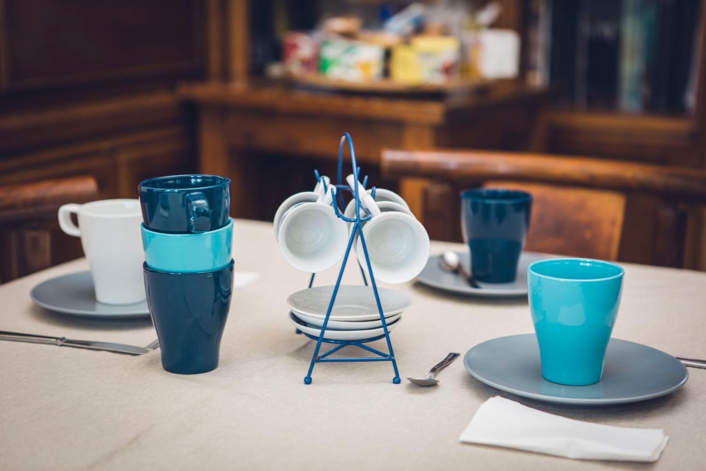 A dining table with a blue and white dish rack, a blue cup, and a white cup.