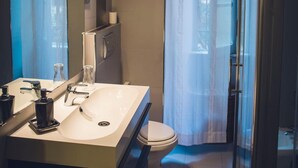 Un baño moderno con un espejo grande, un lavamanos, un inodoro y una zona de ducha.