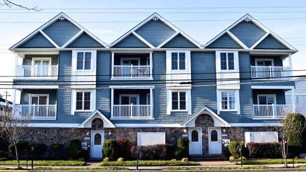 A two-story building with a symmetrical facade, multiple balconies, and a stone foundation. - CLOSE TO ALL, a block from BEACH/BOARDS/ FAMILY FUN..Did we mention HEATED POOL! (Wildwood)
