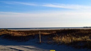 A beach with sand dunes and a pier in the distance. - CLOSE TO ALL, a block from BEACH/BOARDS/ FAMILY FUN..Did we mention HEATED POOL! (Wildwood)