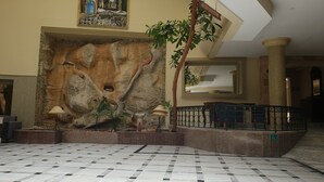 A lobby with a large rock wall, a tiled floor, and a staircase. - Azur Plaza (Hammamet)