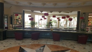 A hotel lobby with a marble floor, a reception desk, red chairs, and large windows with natural light. - Azur Plaza (Hammamet)