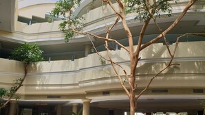 A multi-level atrium with a central tree, marble flooring, and a reception area with a counter and seating. - Azur Plaza (Hammamet)