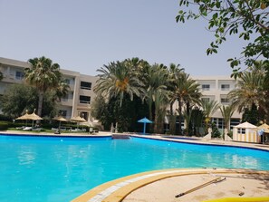 Una piscina cubierta, una piscina al aire libre, sombrillas, tumbonas