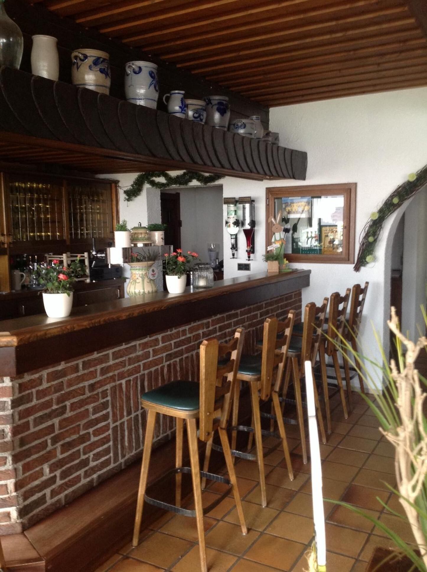 Eine Bar mit einer Ziegel-Theke, Holzsesseln und verschiedenen Barutensilien.