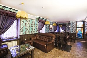 Classic design room with a leather sofa, coffee table, and wooden side table, featuring a large window and a painting on the wall.