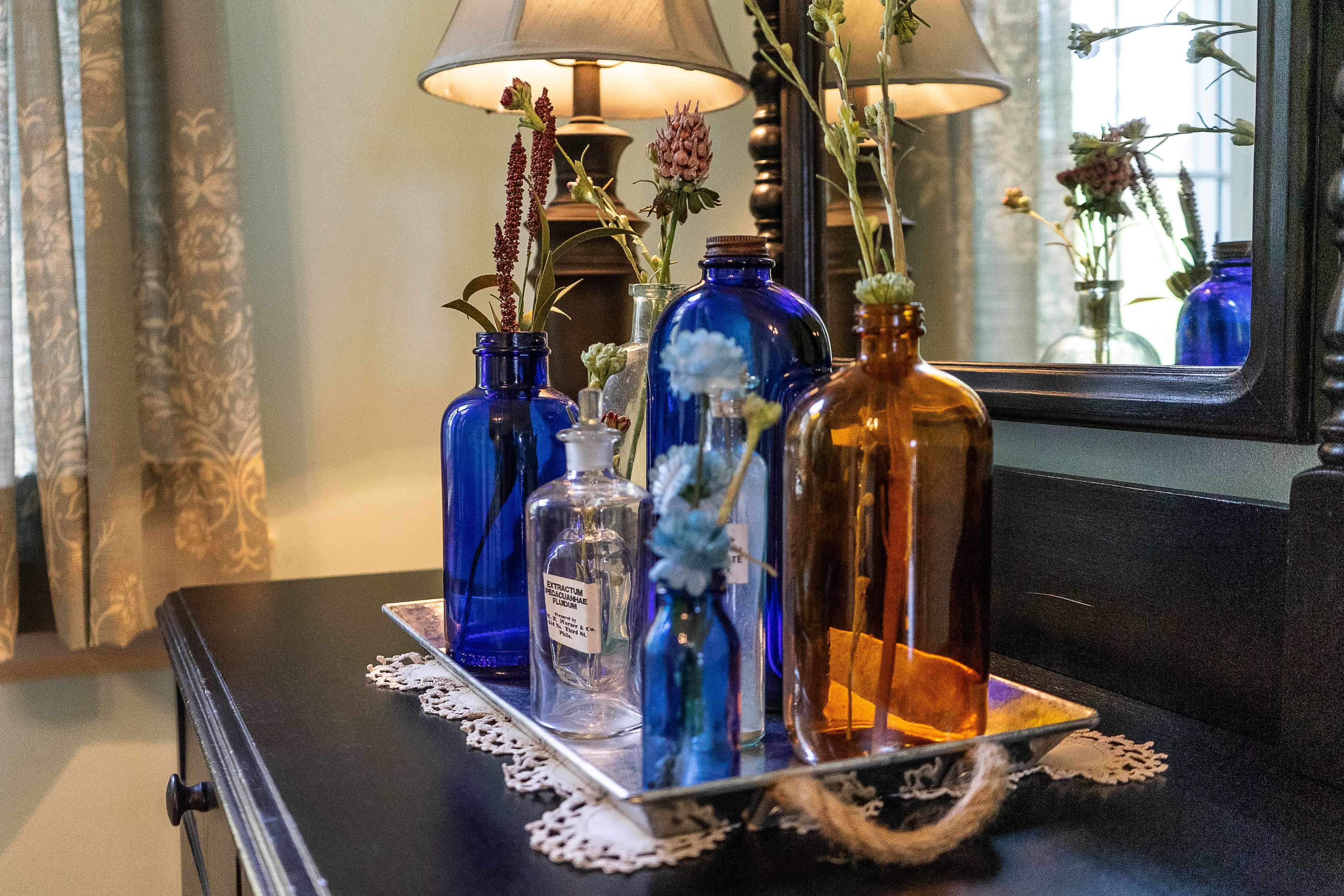 Una mesa con varias botellas de vidrio y una lámpara.