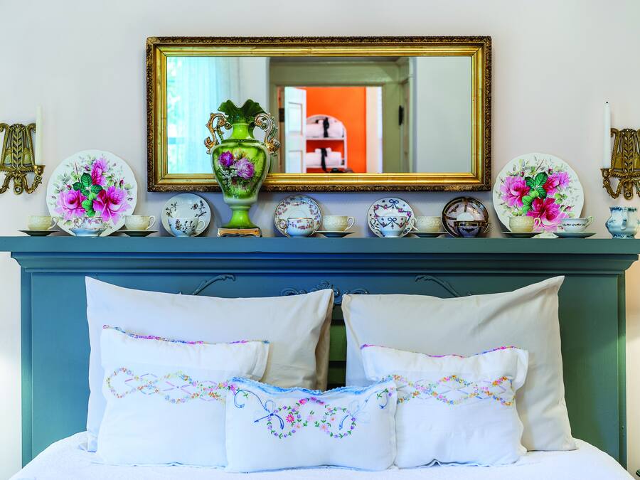 A bedroom with a bed, pillows, a dresser, and a mirror.