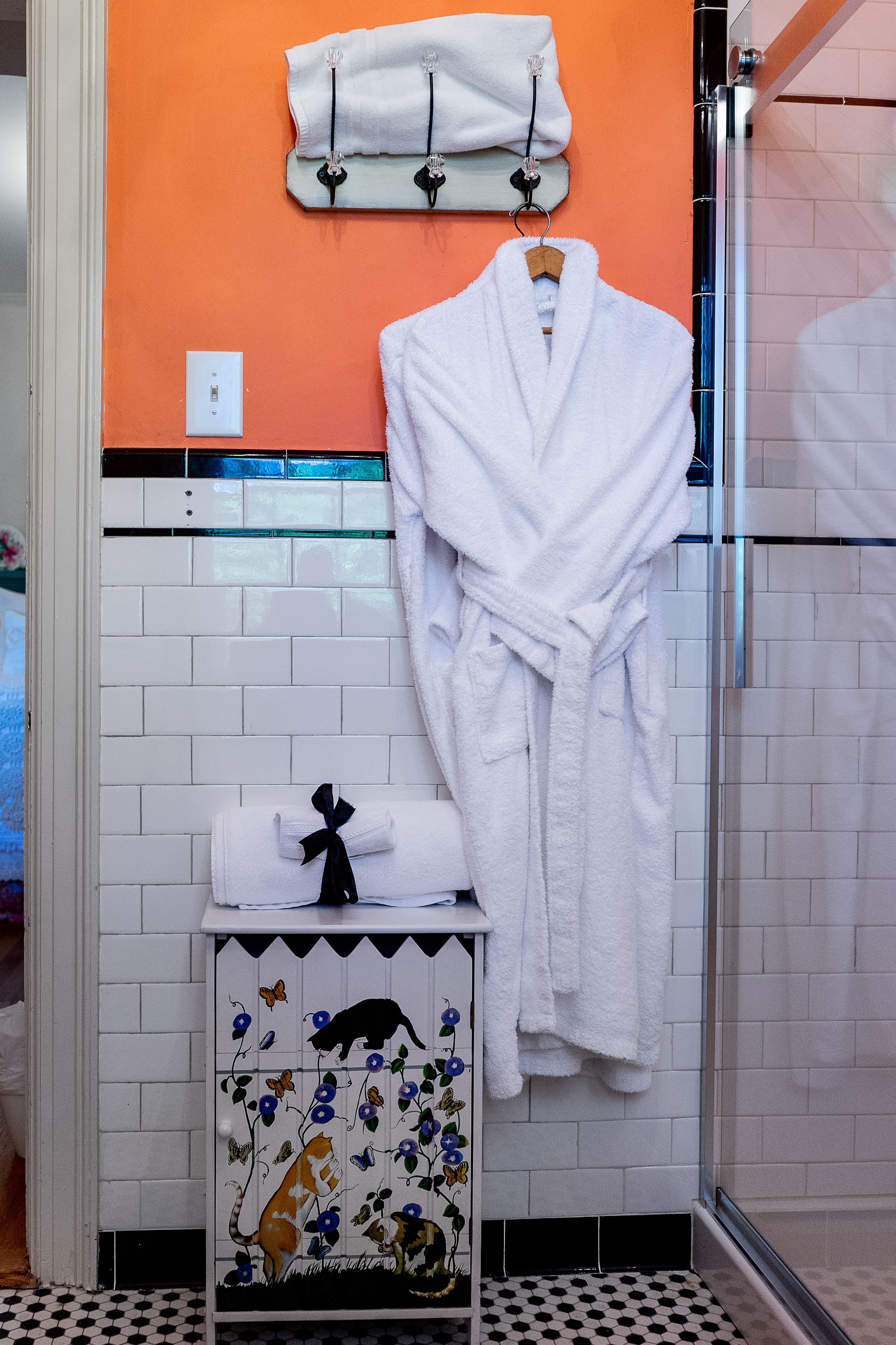 Un baño con una bañera blanca, un perchero blanco y una bata blanca colgada en la pared.