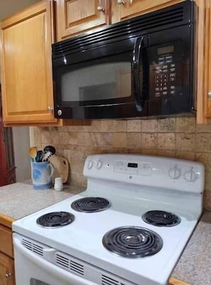 A kitchen with a black microwave above a white stove with four burners. - Fully-Furnished 2-Bedroom/2-Bath Condo ~ Boulder, Colorado - Close to University (Boulder)