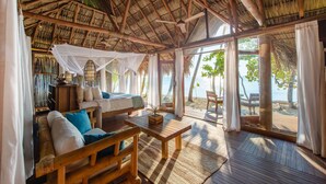 A room with a thatched roof, wooden furniture, and large windows overlooking a beach. - Calala Island (Laguna de Perlas)