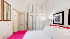 A hotel room with a bed, a wardrobe, and a wall-mounted light fixture. - Elegant apartment Rome (Roma)