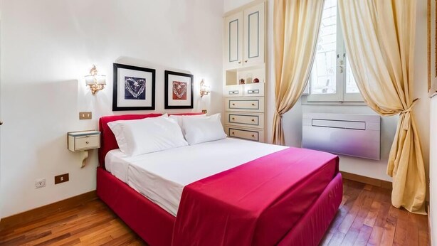 A hotel room with a bed, bedside tables, a wardrobe, and a window with curtains. - Elegant apartment Rome (Roma)