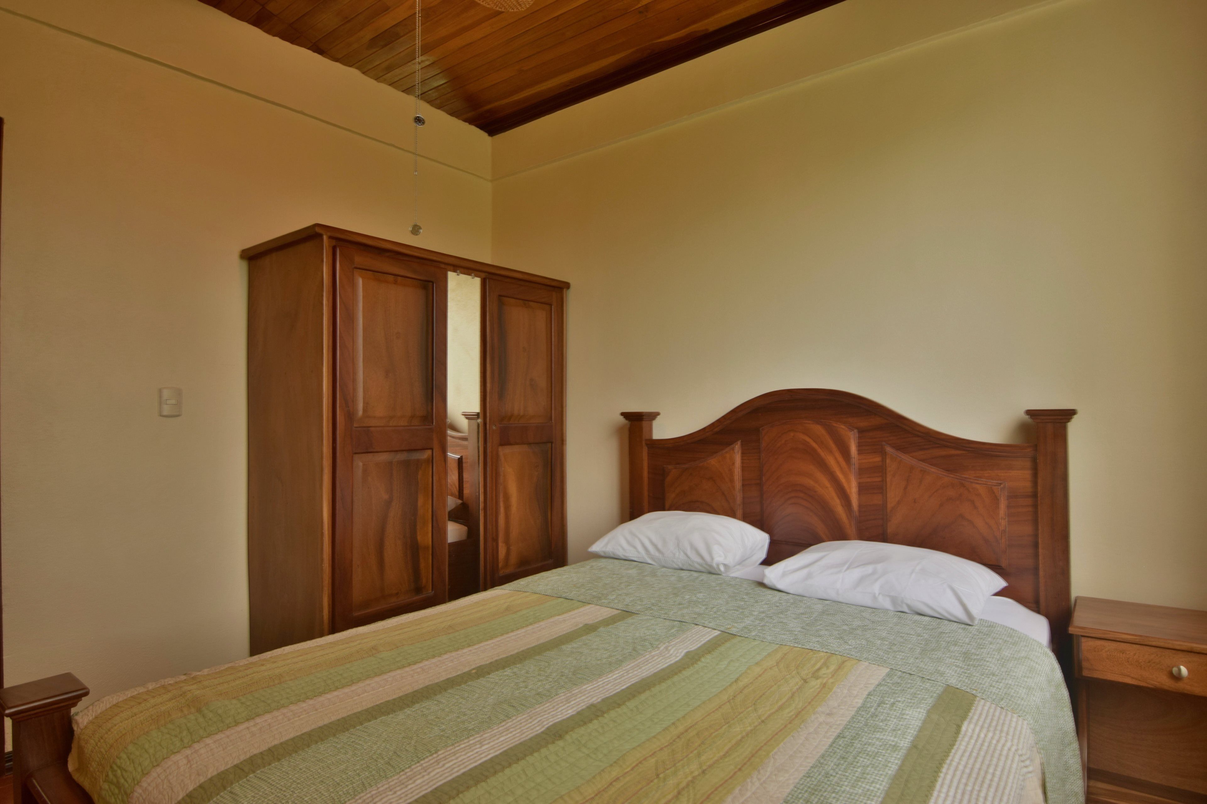 Une chambre à coucher avec un lit en bois, une table de chevet et une armoire.