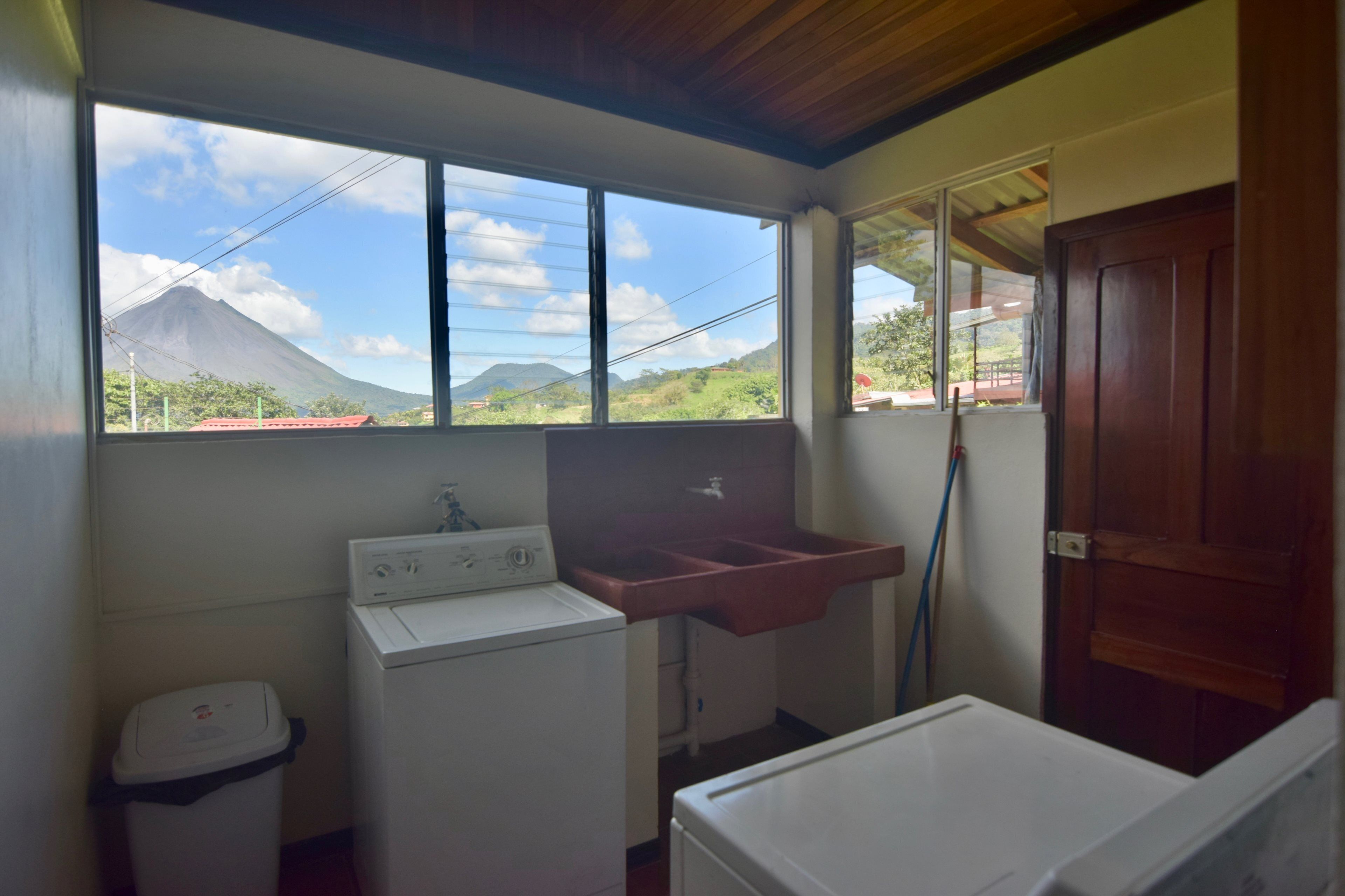 Un cuarto de lavandería con lavadora, un lavamanos y una ventana con vista a la montaña.