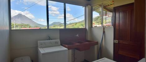 Un cuarto de lavandería con lavadora, un lavamanos y una ventana con vista a la montaña.