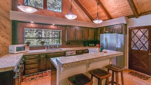 Une cuisine spacieuse dotée d’un grand îlot central, de meubles en bois et offrant une vue sur l’extérieur grâce à une fenêtre.