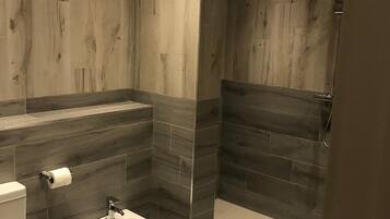 Un baño moderno con inodoro, bidé y zona de ducha.