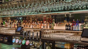 A bar area with multiple shelves of liquor bottles and glasses. - Village Hotel (Bettystown)