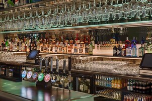 Zona de bar con varias estanterías llenas de botellas de licor y vasos.