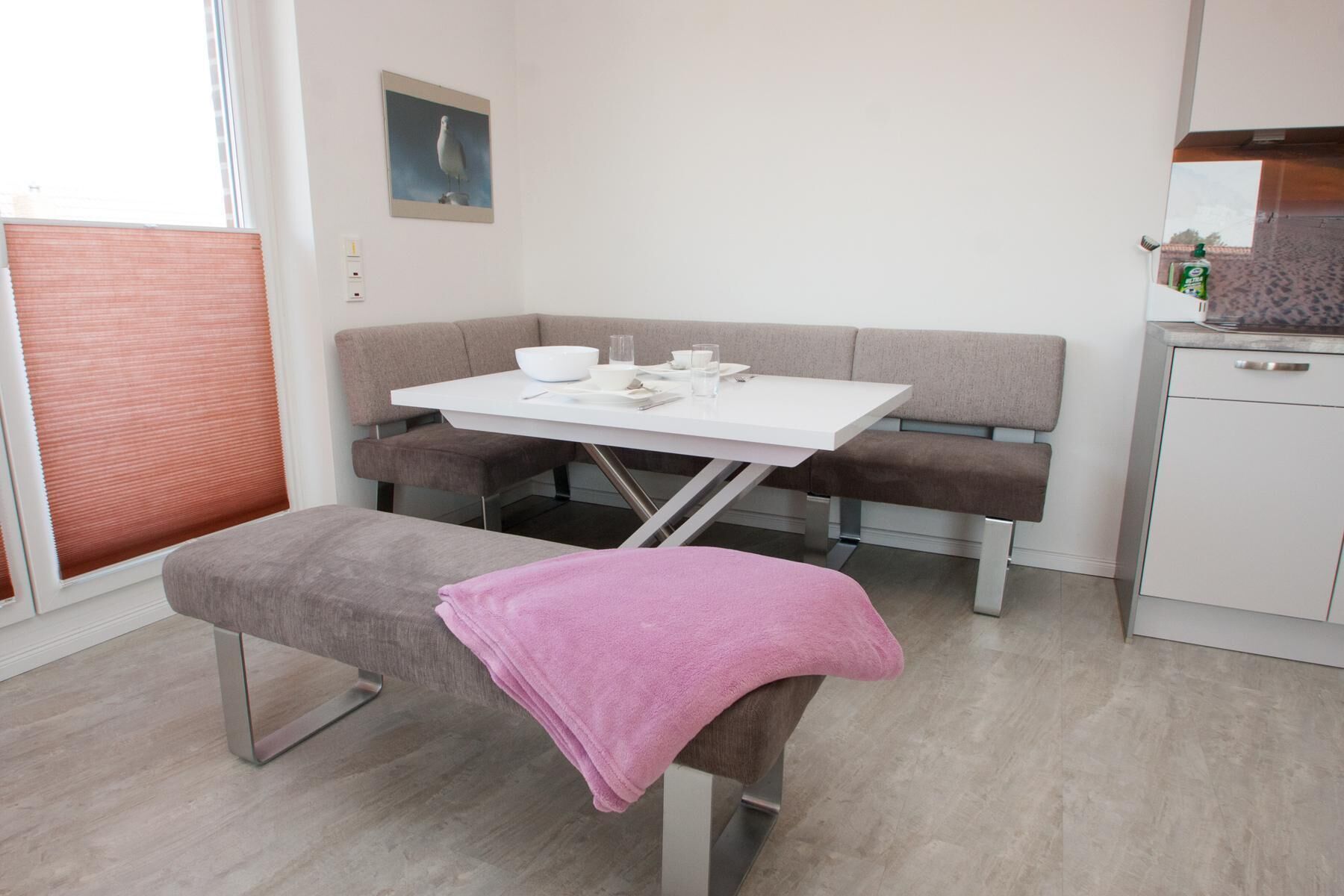 A modern, minimalist room with a white table, bench, and bench seat.